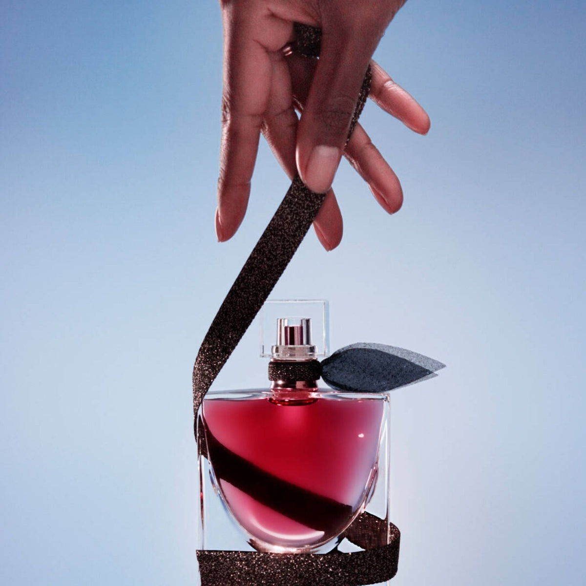 Refect Beauty Lancome La Vie Est Belle L'Elixir perfume bottle held by a hand with a dark glittery ribbon