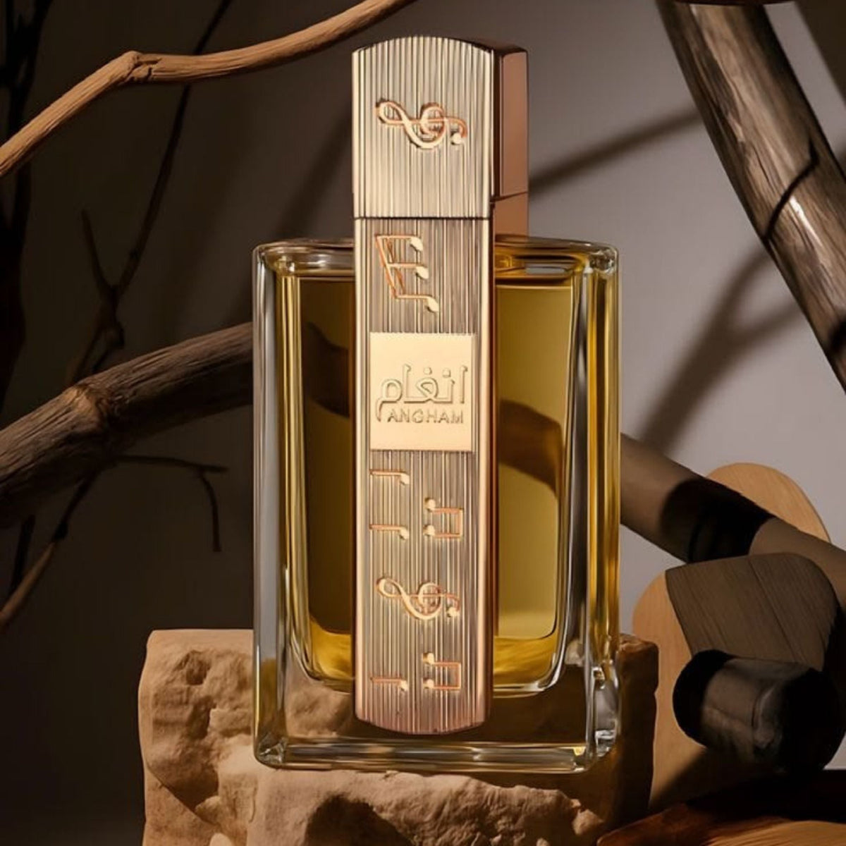 Refect Beauty Lattafa Angham Eau de Parfum bottle with gold musical note accents, set on stone against rustic branches.