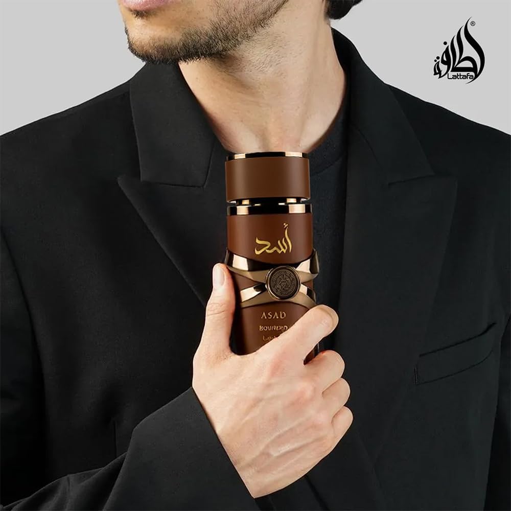 Refect Beauty Lattafa Asad Bourbon eau de parfum bottle held by a man in a black suit, featuring a dark brown cap.