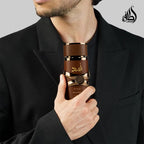Refect Beauty Lattafa Asad Bourbon eau de parfum bottle held by a man in a black suit, featuring a dark brown cap.