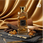 Refect Beauty Lattafa Oud Mood Elixir perfume bottle with gold ribbon on a slate base with oud wood and amber resin