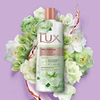 Refect Beauty Lux Silky Gardenia body wash bottle surrounded by fresh white gardenia flowers on a purple background.