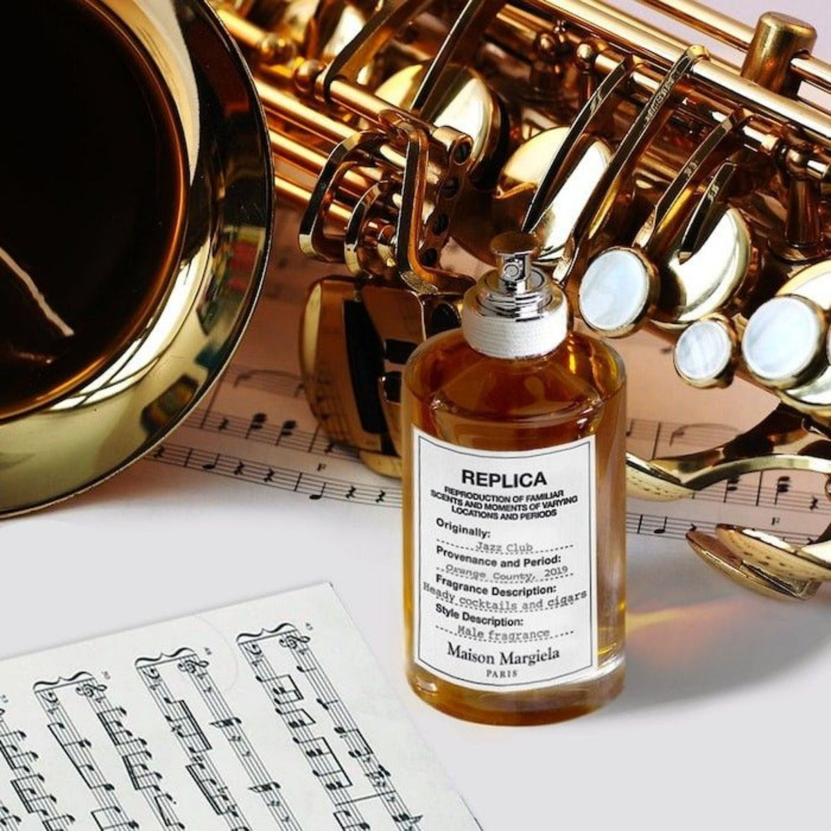 Refect Beauty Maison Margiela Replica Jazz Club perfume bottle next to a golden saxophone and sheet music.