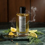 Refect Beauty Mancera Cedrat Boise Intense perfume bottle on a marble surface with citrus slices and wisps of smoke.