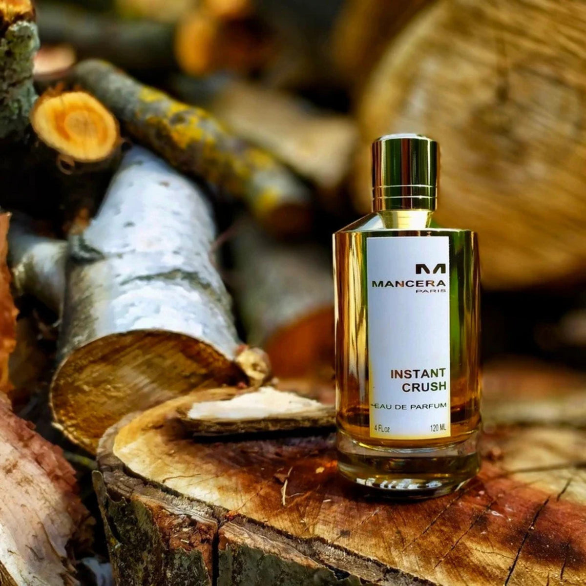 Refect Beauty Mancera Paris Instant Crush Eau de Parfum bottle resting on rustic wooden logs in a natural setting.