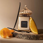 Refect Beauty Matin Martin Miral perfume bottle with gold finish, vanilla beans, and orange slices on wood slice.