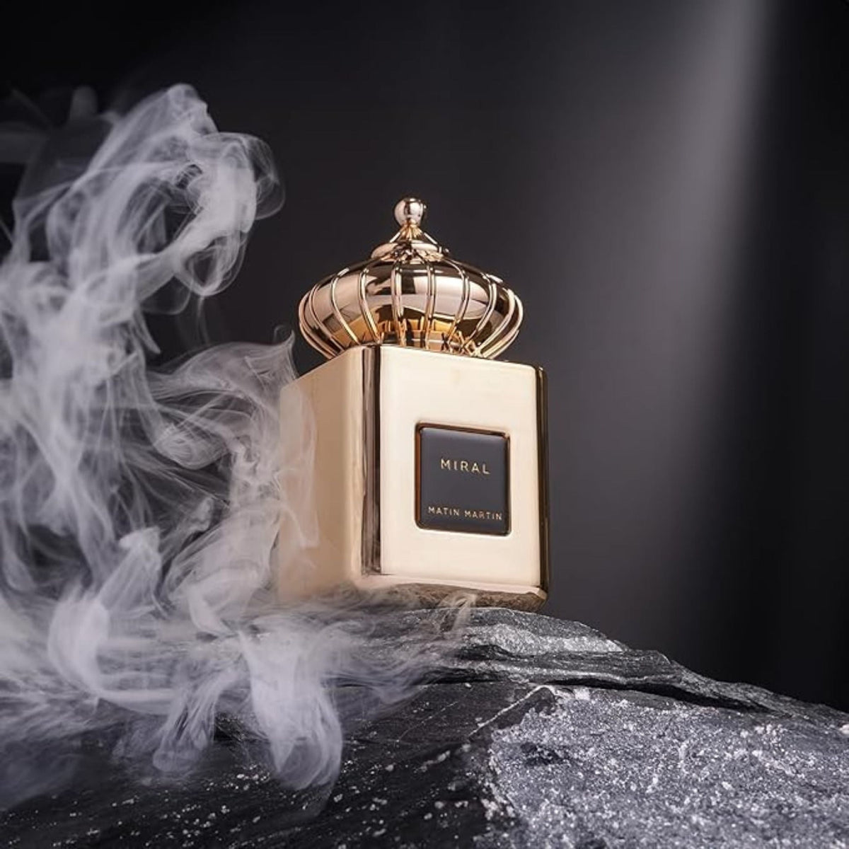 Refect Beauty Matin Martin Miral perfume bottle with a gold crown cap resting on a dark stone surrounded by smoke