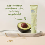 Refect Beauty Mustela Multi-purpose Balm in a recyclable aluminum tube next to a fresh avocado on a marble tray.