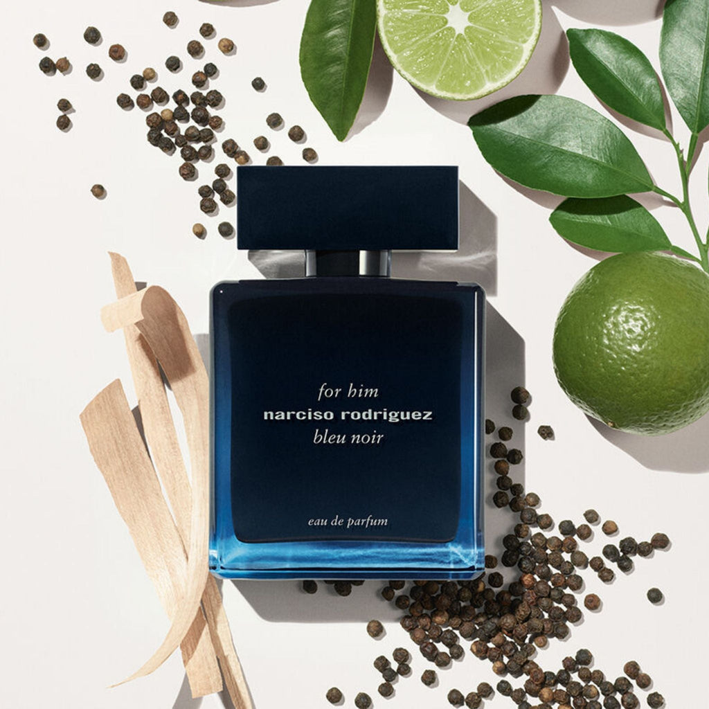 Refect Beauty Narciso Rodriguez For Him Bleu Noir Eau de Parfum bottle surrounded by bergamot, pepper, and wood chips.