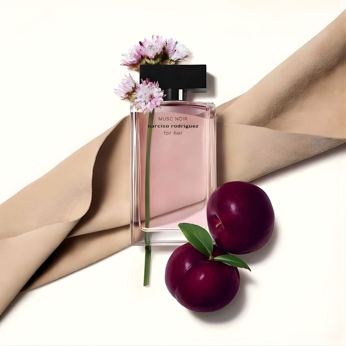 Refect Beauty Narciso Rodriguez Musc Noir perfume bottle with pink liquid, fresh plums, and suede fabric on white