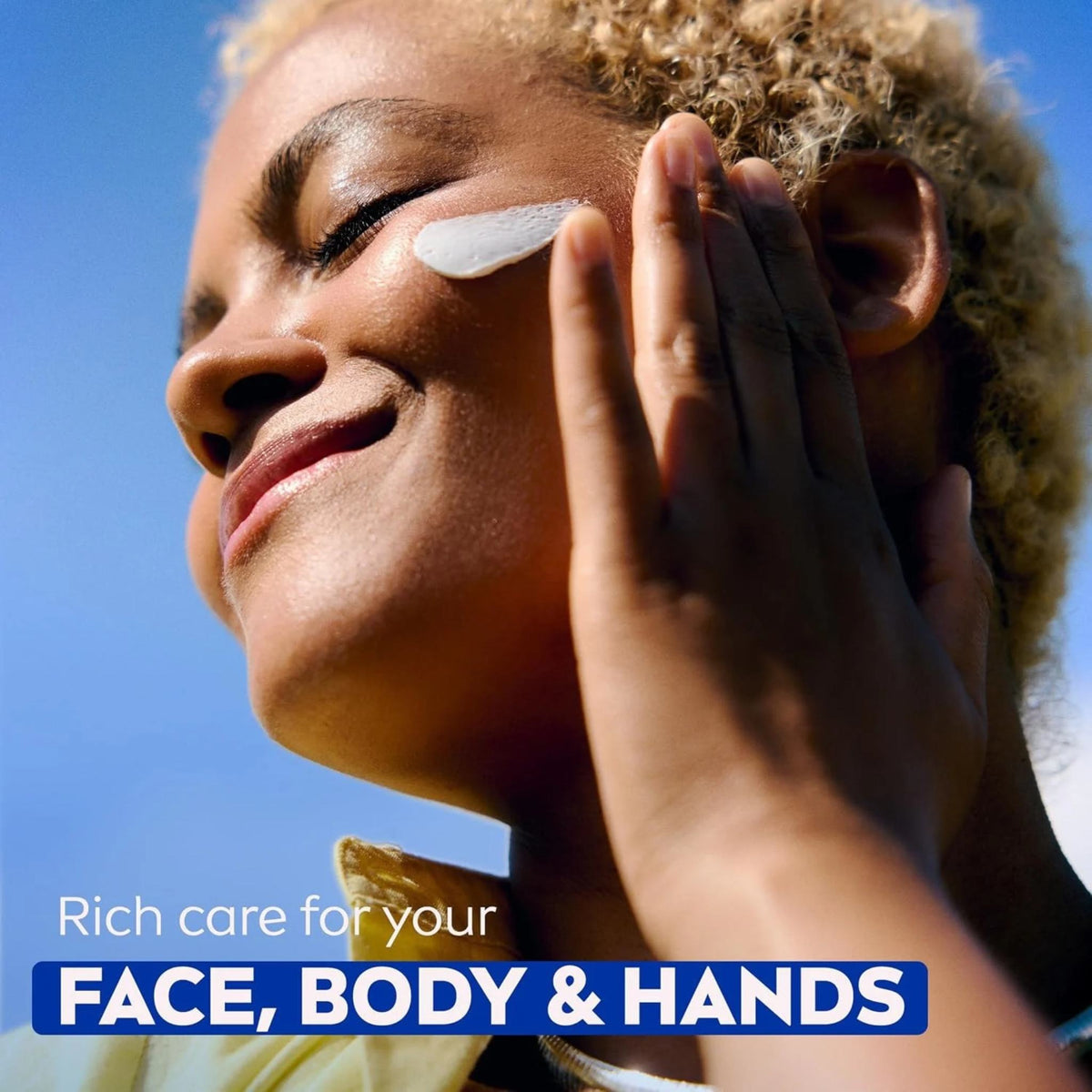 Refect Beauty model applying rich Nivea Creme to her cheek for intensive hydration against a bright blue sky