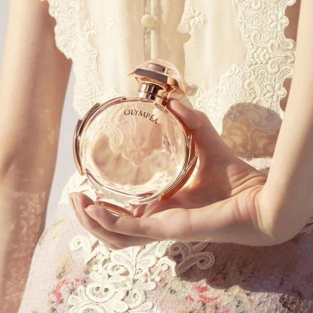 Refect Beauty Paco Rabanne Olympea Eau de Parfum bottle held in hand, featuring a rose gold cap and circular glass.