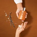 Refect Beauty Parfums de Marly Althaïr bottle held in hand with vanilla beans and orange blossom on brown background