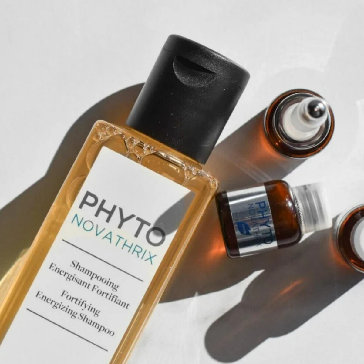 Refect Beauty Phyto Novathrix fortifying energizing shampoo bottle with small treatment vials on a white surface