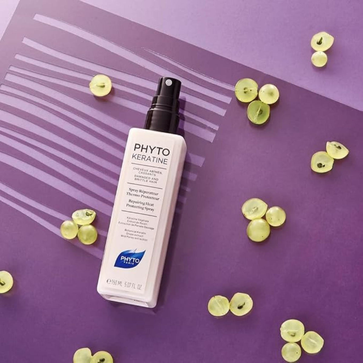 Refect Beauty Phyto Phytokeratine heat protecting hair spray bottle on a purple background with fresh grape slices