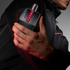 Refect Beauty Prada Luna Rossa Carbon Eau de Toilette bottle held by a man in a black jacket with red lighting