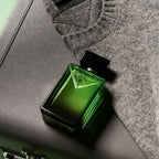 Refect Beauty Prada Paradigme Eau de Parfum bottle in green glass on a textured surface next to a grey knit sweater.
