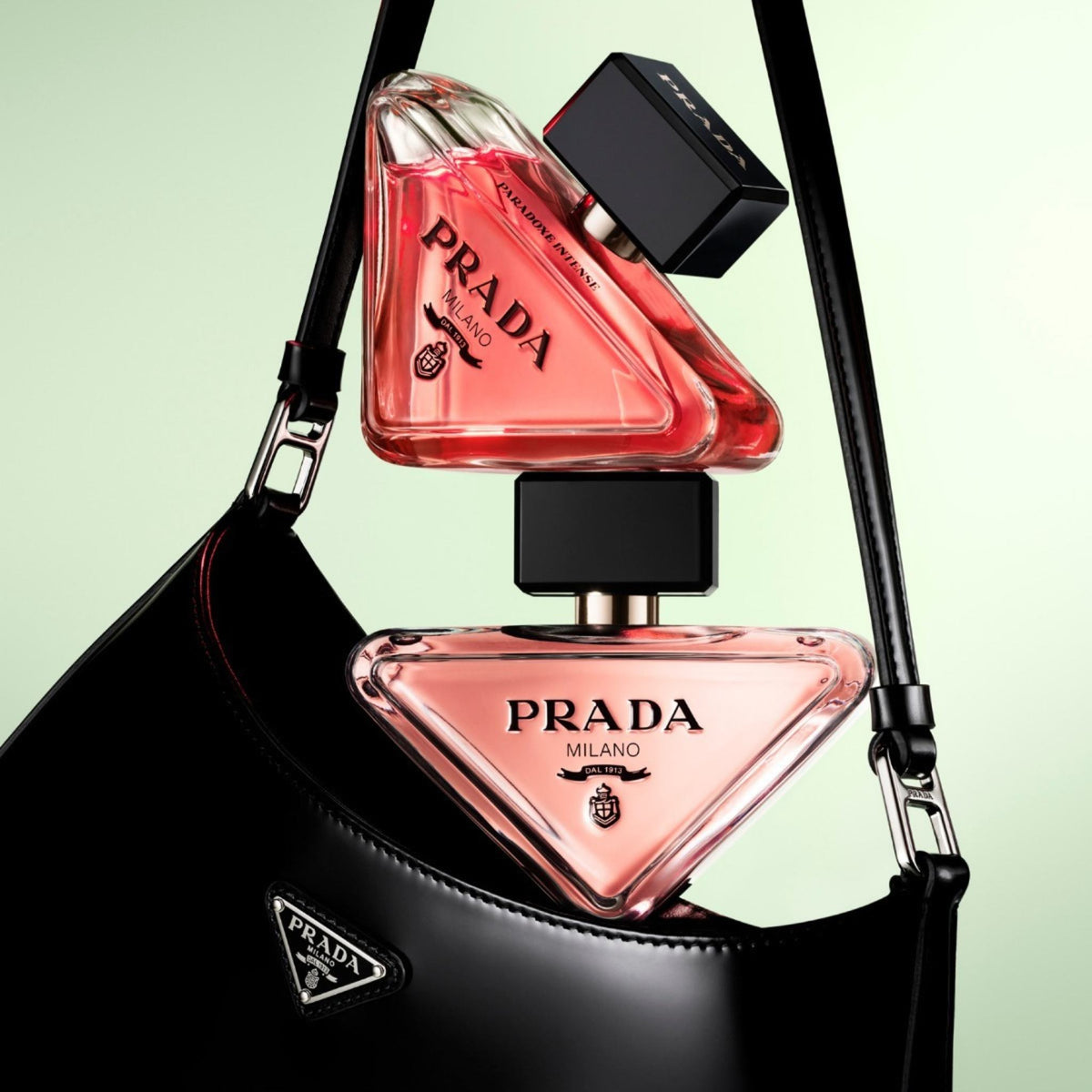 Refect Beauty Prada Paradoxe Intense perfume bottles in iconic triangular glass resting on a black Prada handbag