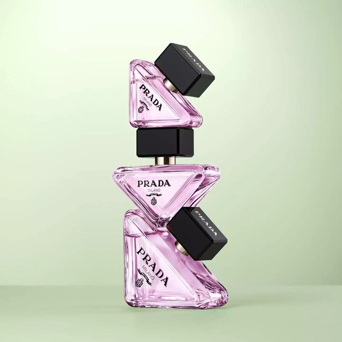 Refect Beauty Prada Paradoxe Virtual Flower perfume bottles stacked in a triangular arrangement on a green background