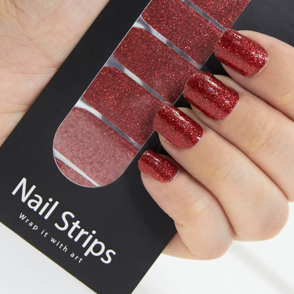 Refect Beauty Yolo nail strips featuring a vibrant red glitter finish applied to fingernails for a salon-style look.