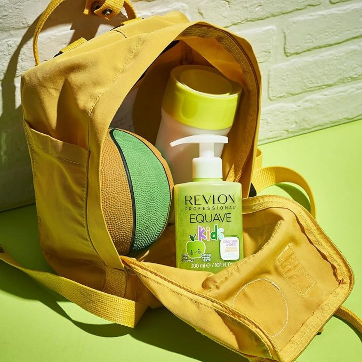 Refect Beauty Revlon Professional Equave Kids Green Apple Shampoo bottle inside a yellow backpack with a toy ball.