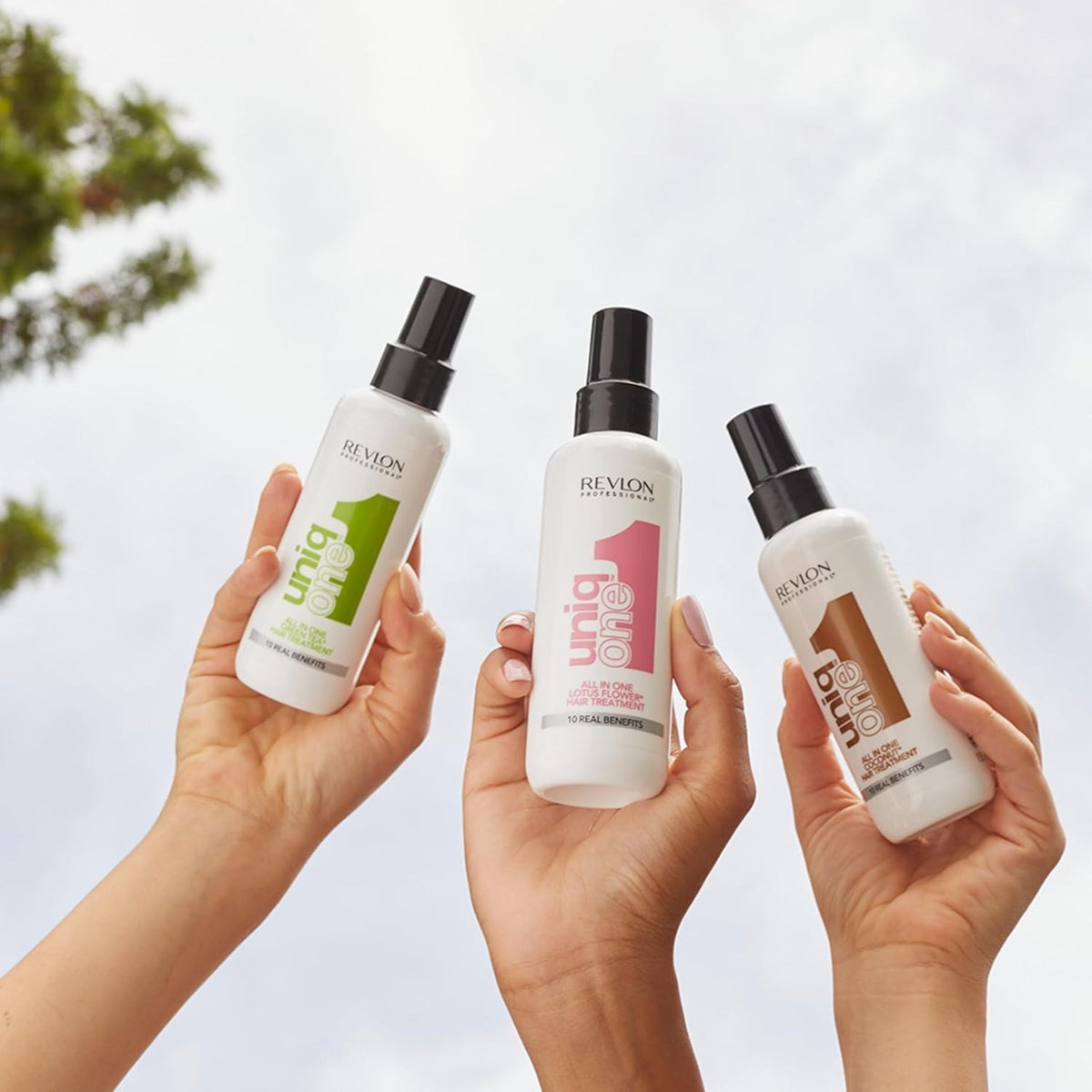 Refect Beauty presents three Revlon Uniq One leave-in hair treatment spray bottles held up against a bright sky.