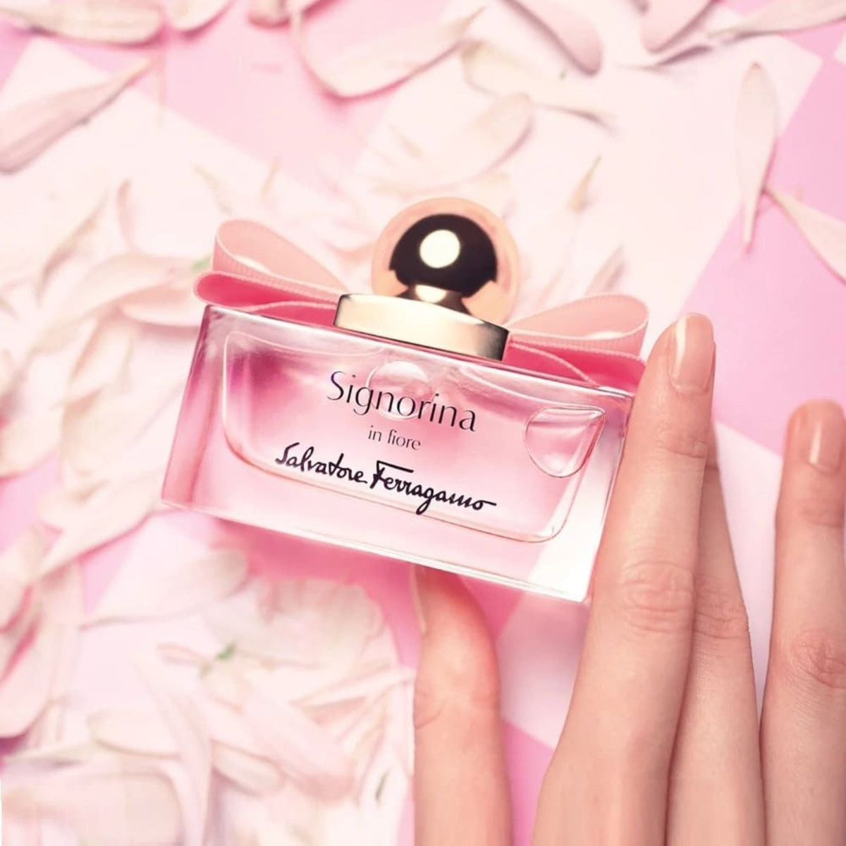 Refect Beauty Salvatore Ferragamo Signorina In Fiore perfume bottle with a pink bow on a background of flower petals