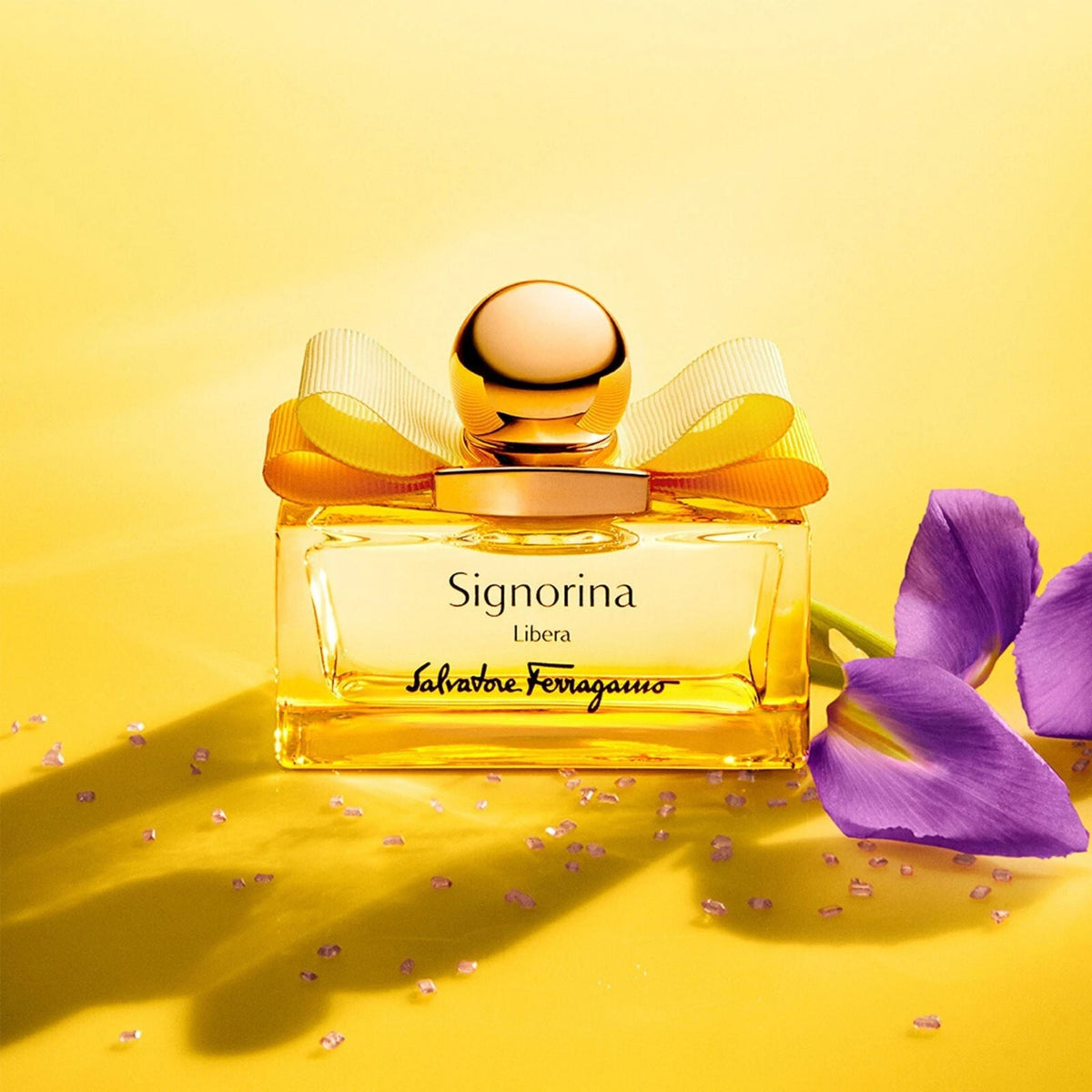 Refect Beauty Salvatore Ferragamo Signorina Libera perfume bottle with a gold bow on a bright yellow background