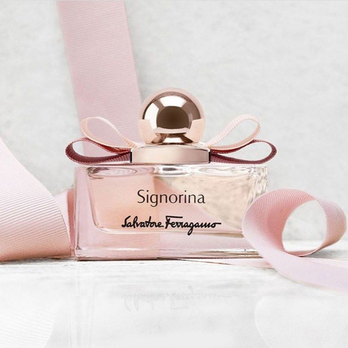 Refect Beauty Salvatore Ferragamo Signorina Eau de Parfum bottle with a pink ribbon bow on a white surface