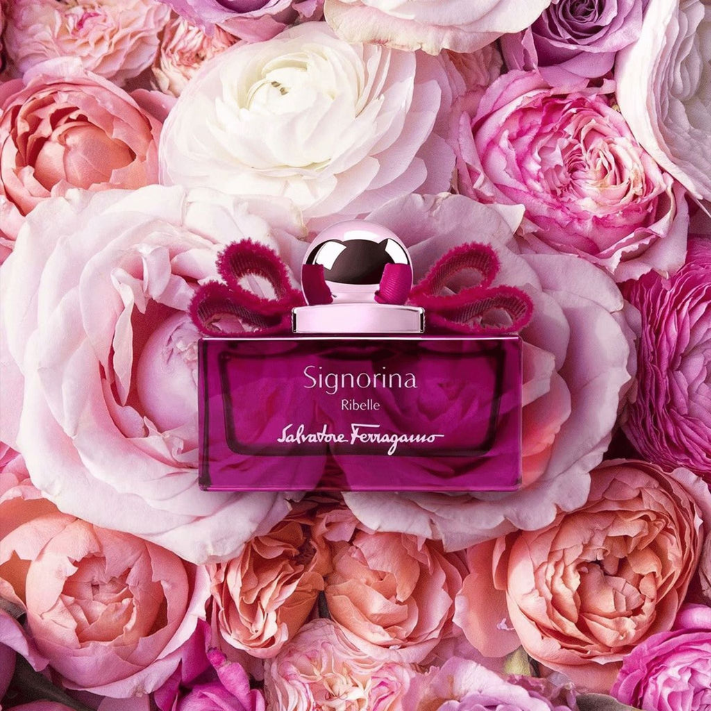 Refect Beauty Salvatore Ferragamo Signorina Ribelle perfume bottle with a pink bow, set against a bed of pink roses.