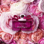 Refect Beauty Salvatore Ferragamo Signorina Ribelle perfume bottle with a pink bow, set against a bed of pink roses.
