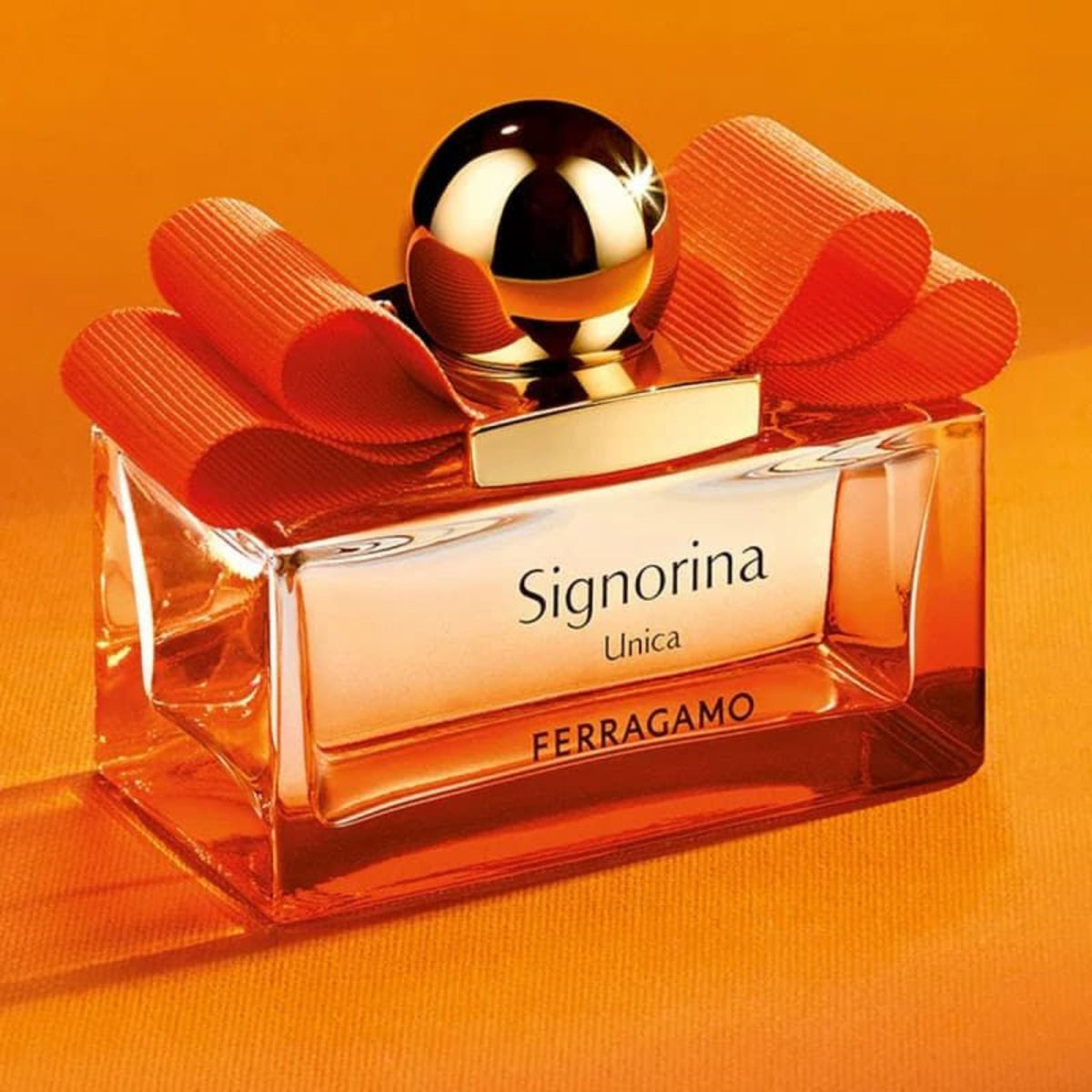 Refect Beauty Salvatore Ferragamo Signorina Unica perfume bottle with orange glass, gold cap, and signature bow