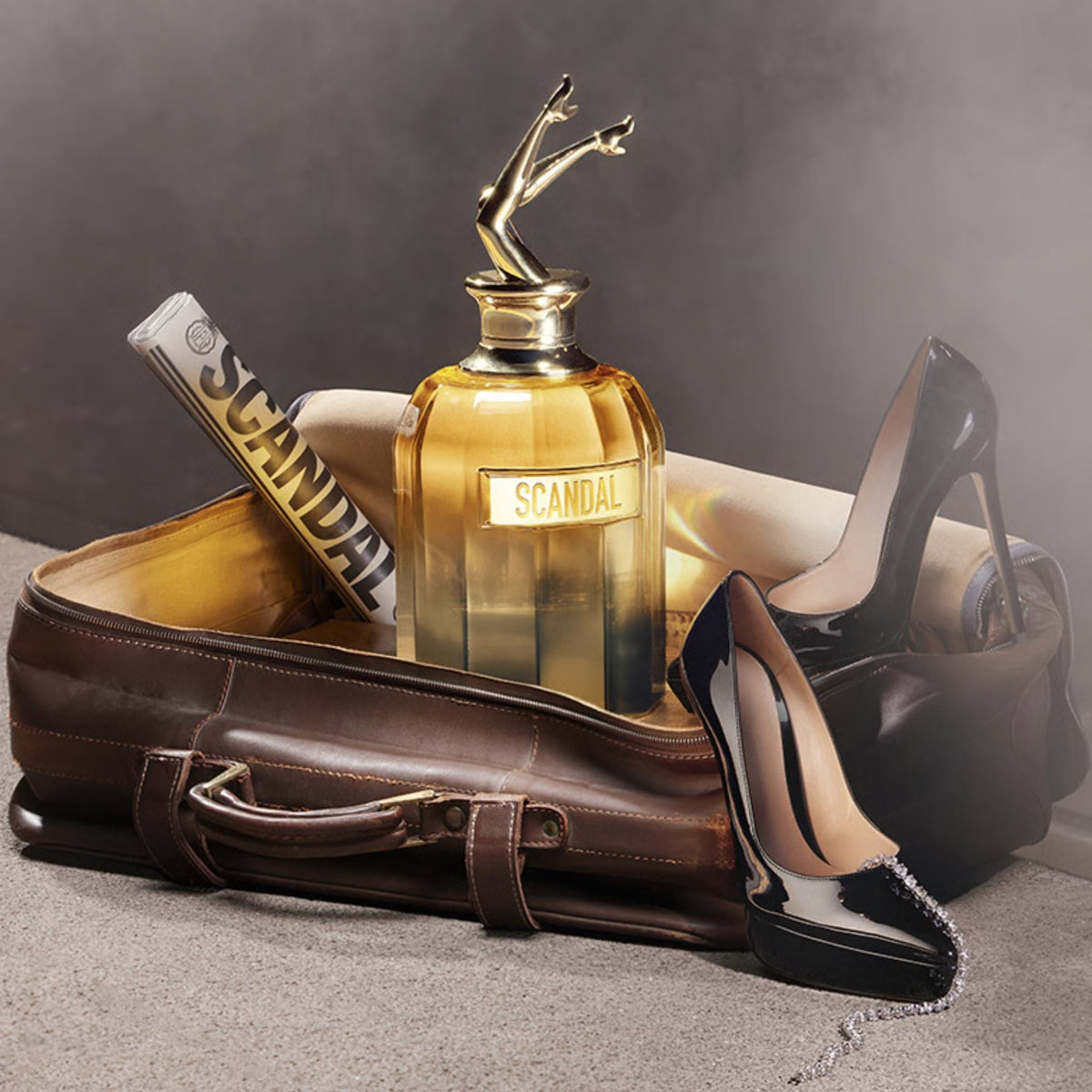 Refect Beauty Jean Paul Gaultier Scandal Absolu perfume bottle with iconic legs cap inside a vintage leather suitcase.