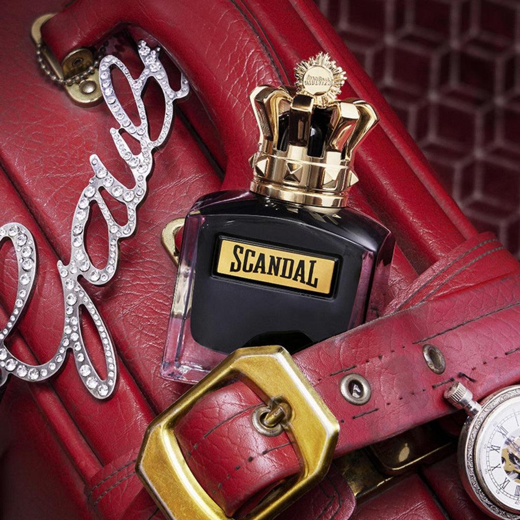 Refect Beauty Jean Paul Gaultier Scandal Pour Homme fragrance bottle with a gold crown cap on a red leather background