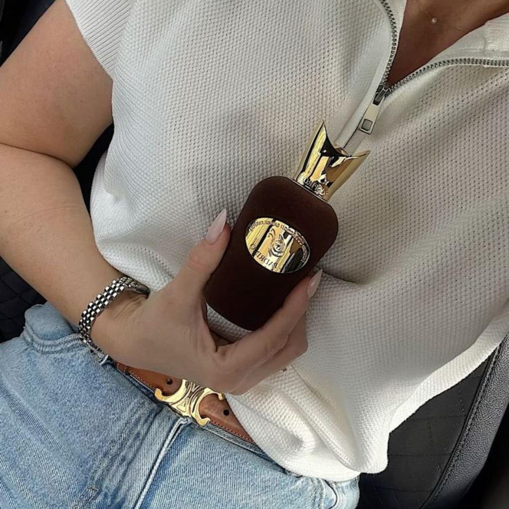 Refect Beauty Sospiro Il Padrino Eau de Parfum bottle with a dark brown velvet finish and gold cap held in a hand