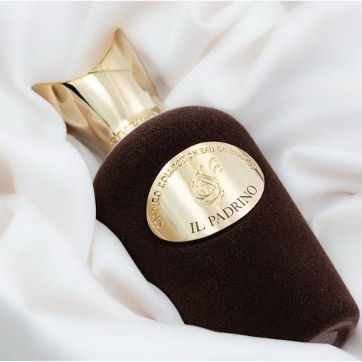 Refect Beauty Sospiro Il Padrino Eau de Parfum in a dark brown velvet bottle with a gold cap on white fabric.