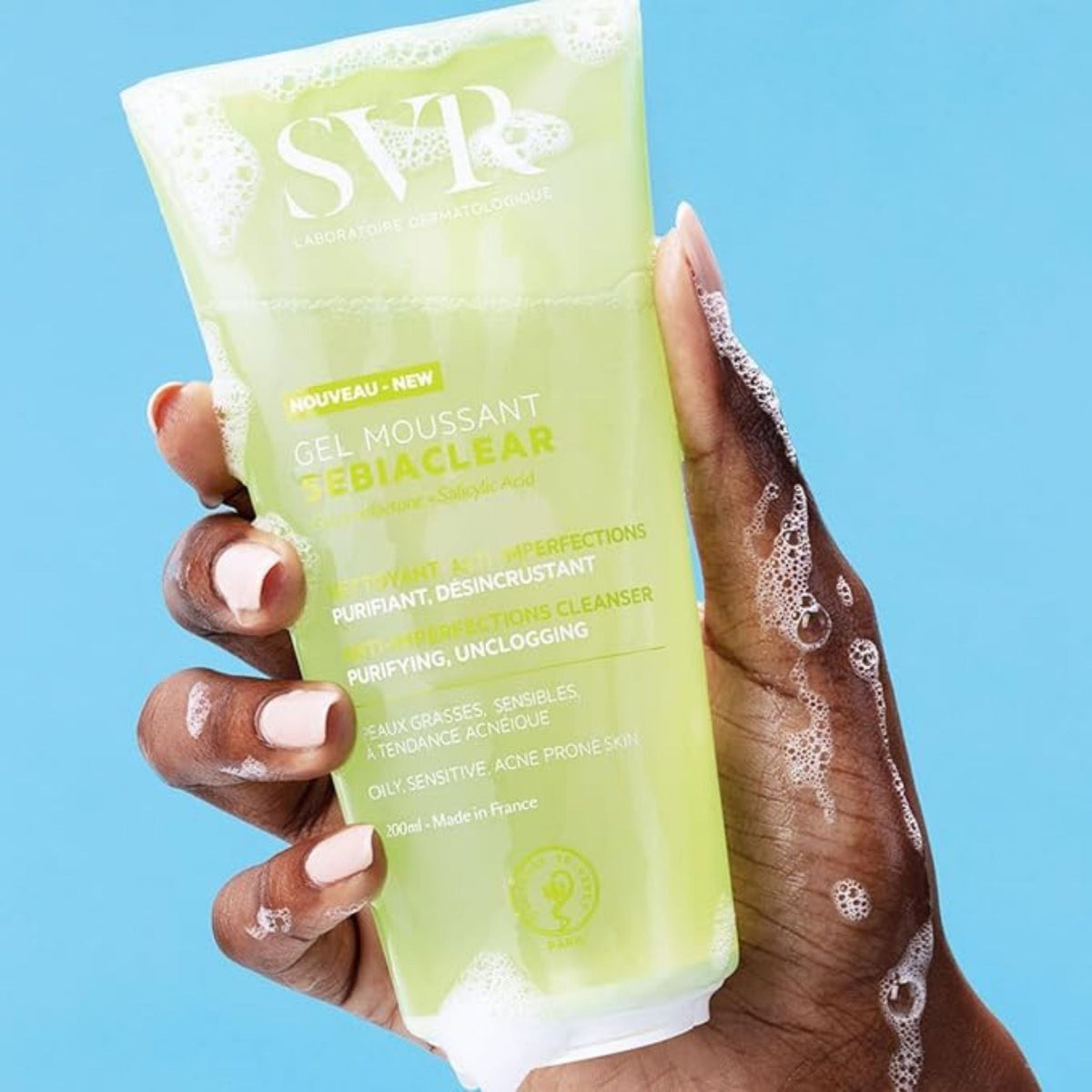 Refect Beauty SVR Sebiaclear Gel Moussant foaming cleanser held in hand against a blue background