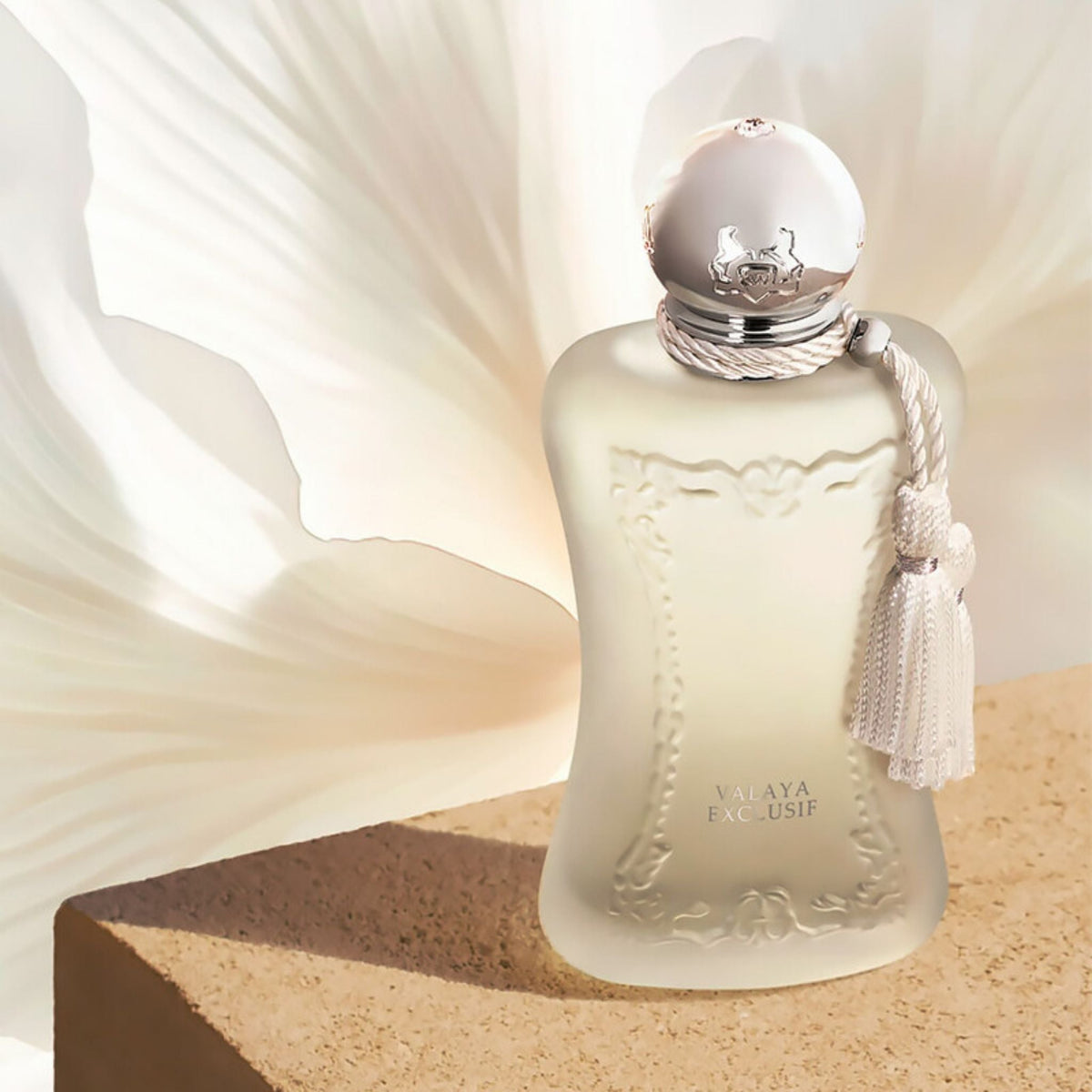 Refect Beauty Parfums de Marly Valaya Exclusif perfume bottle with a white tassel, set against a soft floral backdrop.