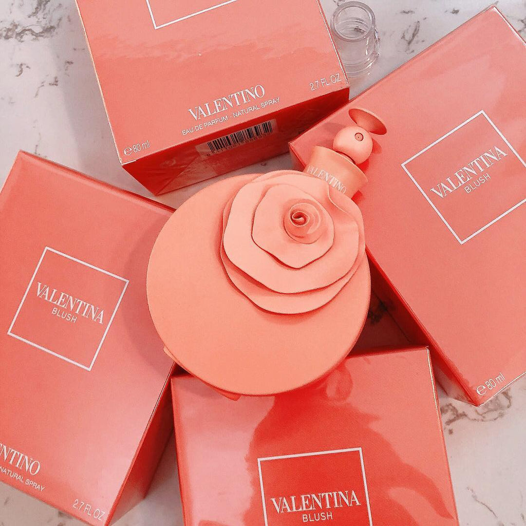 Refect Beauty Valentino Blush eau de parfum bottle with a rose-shaped cap surrounded by coral pink product boxes