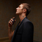 Refect Beauty model applying Valentino Born in Roma Uomo Extradose perfume to his neck in a dark, elegant setting.