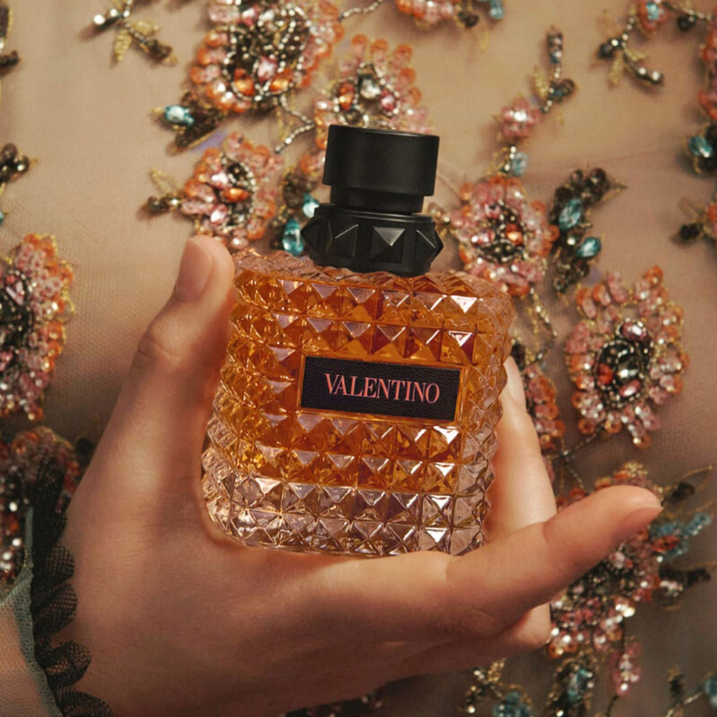 Refect Beauty Valentino Donna Born in Roma Coral Fantasy perfume bottle held in hand against a floral embroidered dress