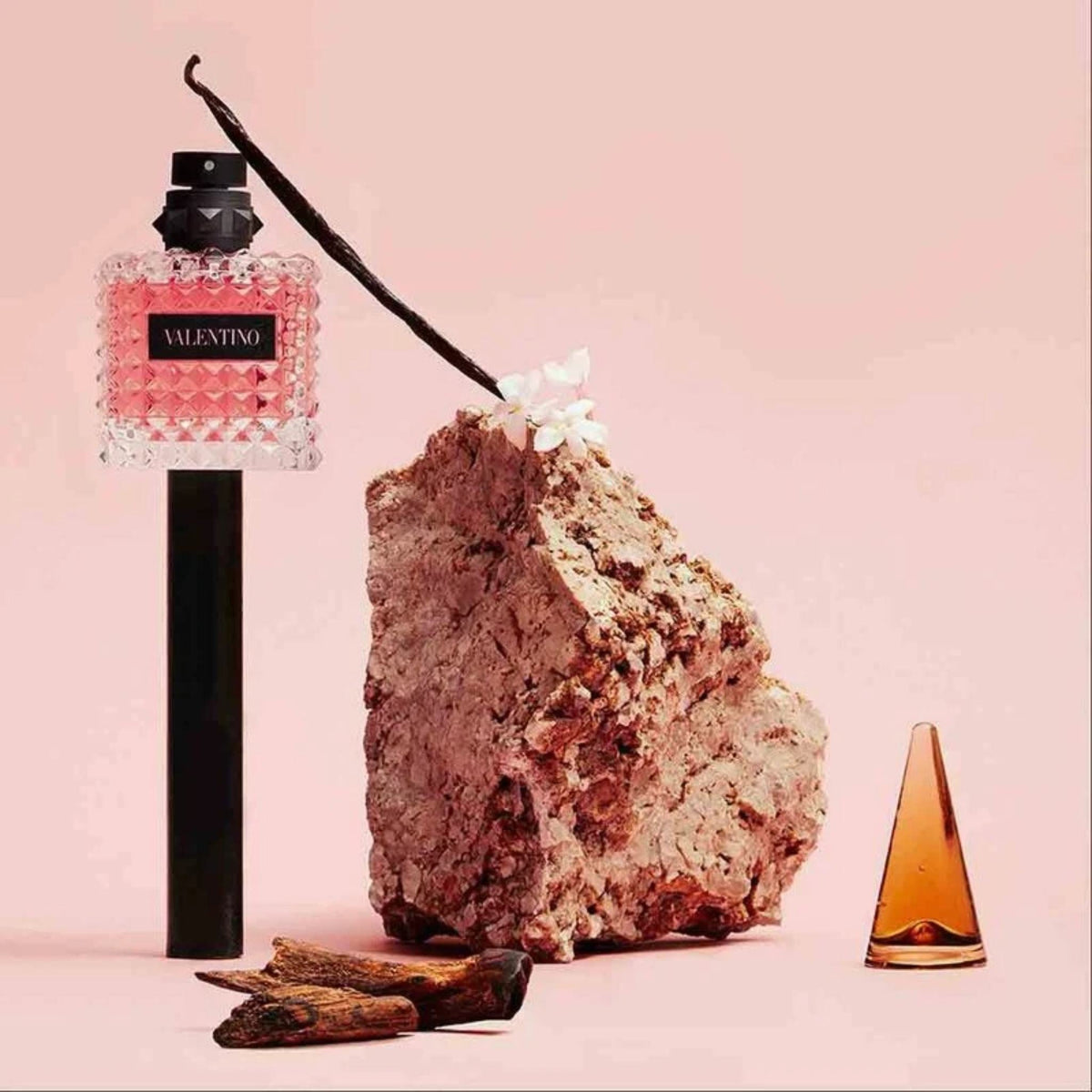 Refect Beauty Valentino Donna Born In Roma perfume bottle with vanilla bean, jasmine, and wood on a pink background