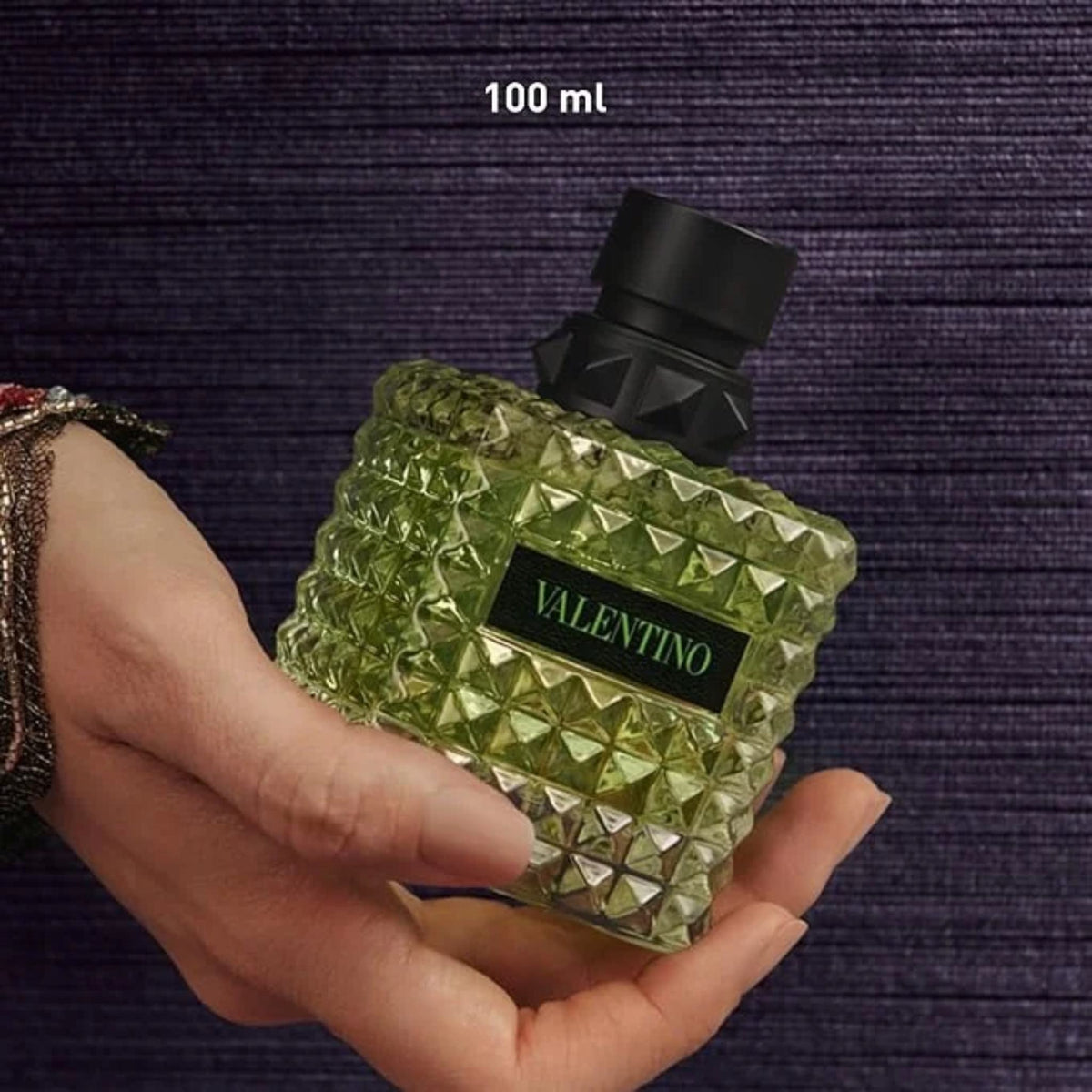 Refect Beauty Valentino Donna Born In Roma Green Stravaganza perfume bottle held in hand against a textured background