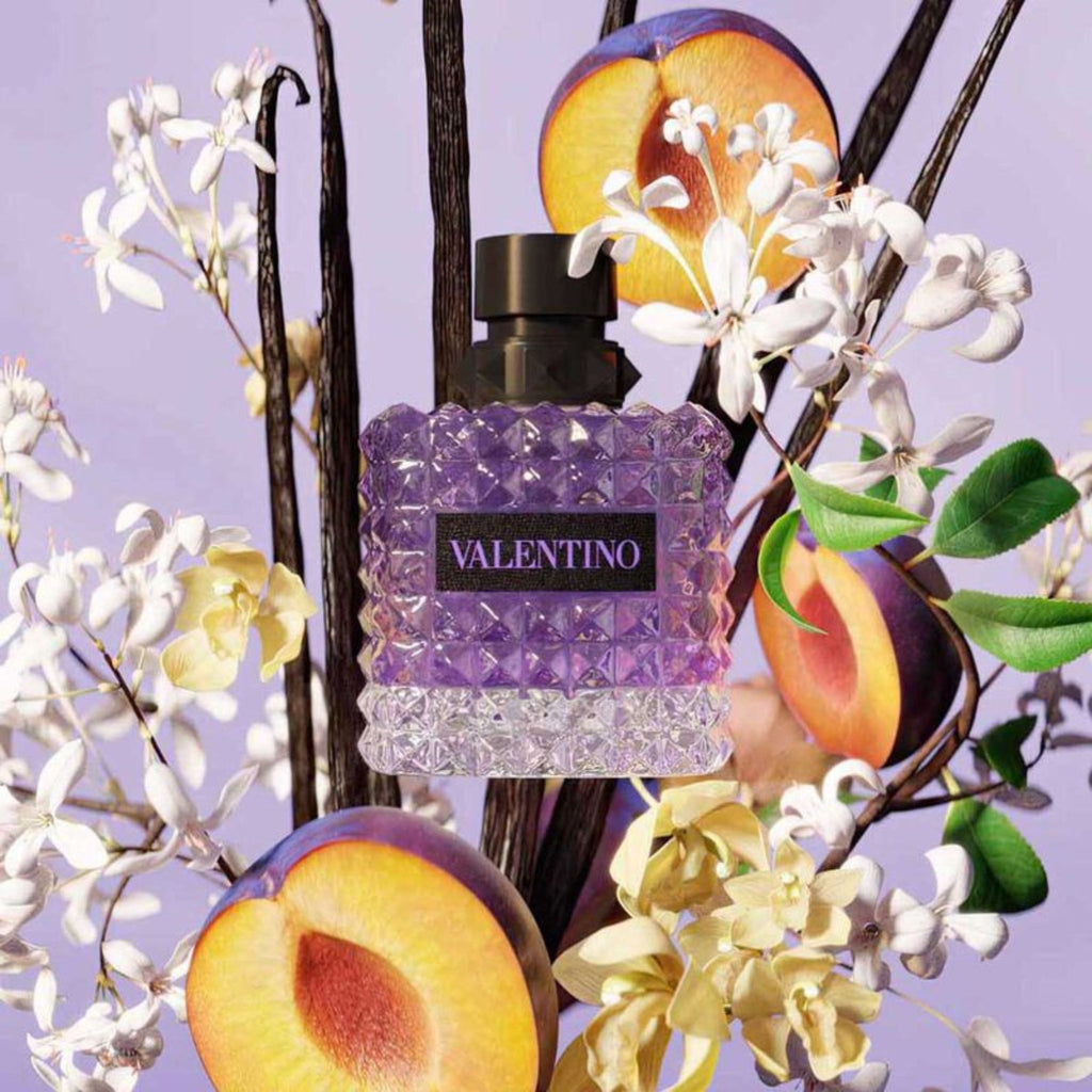 Refect Beauty Valentino Donna Born In Roma Purple Melancholia perfume bottle surrounded by fresh plums and jasmine