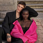 Refect Beauty campaign featuring a man in a black suit and a woman in a bright pink blazer posing on stone steps.