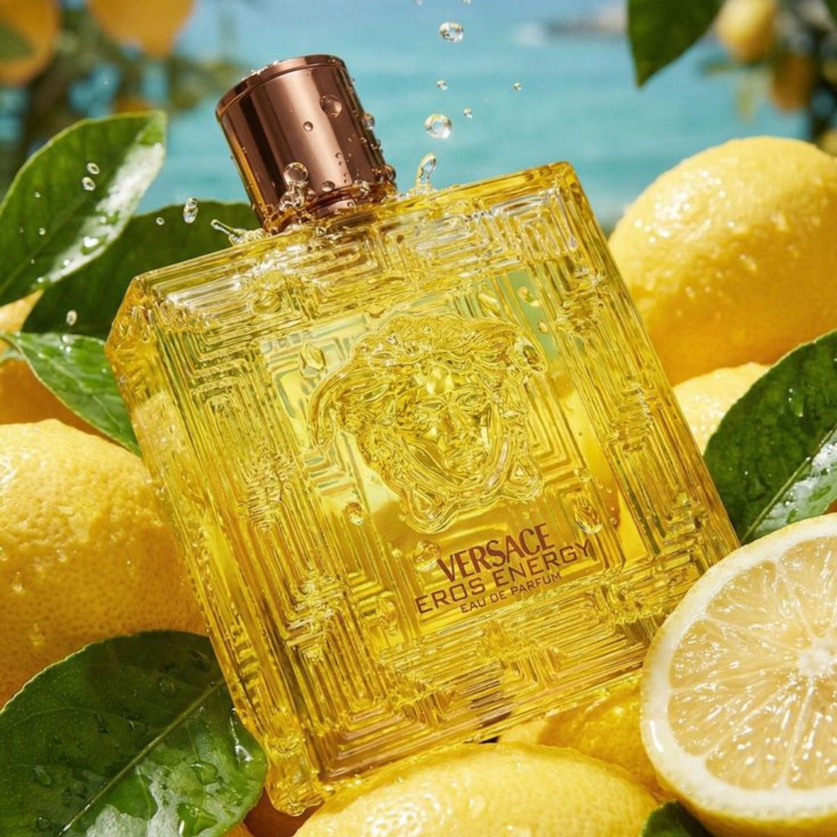 Refect Beauty Versace Eros Energy Eau de Parfum bottle surrounded by fresh lemons and water splashes in a sunny setting