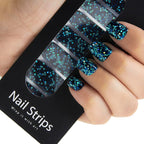 Refect Beauty Yolo nail strips featuring a black base with vibrant blue and teal glitter for a salon-style manicure