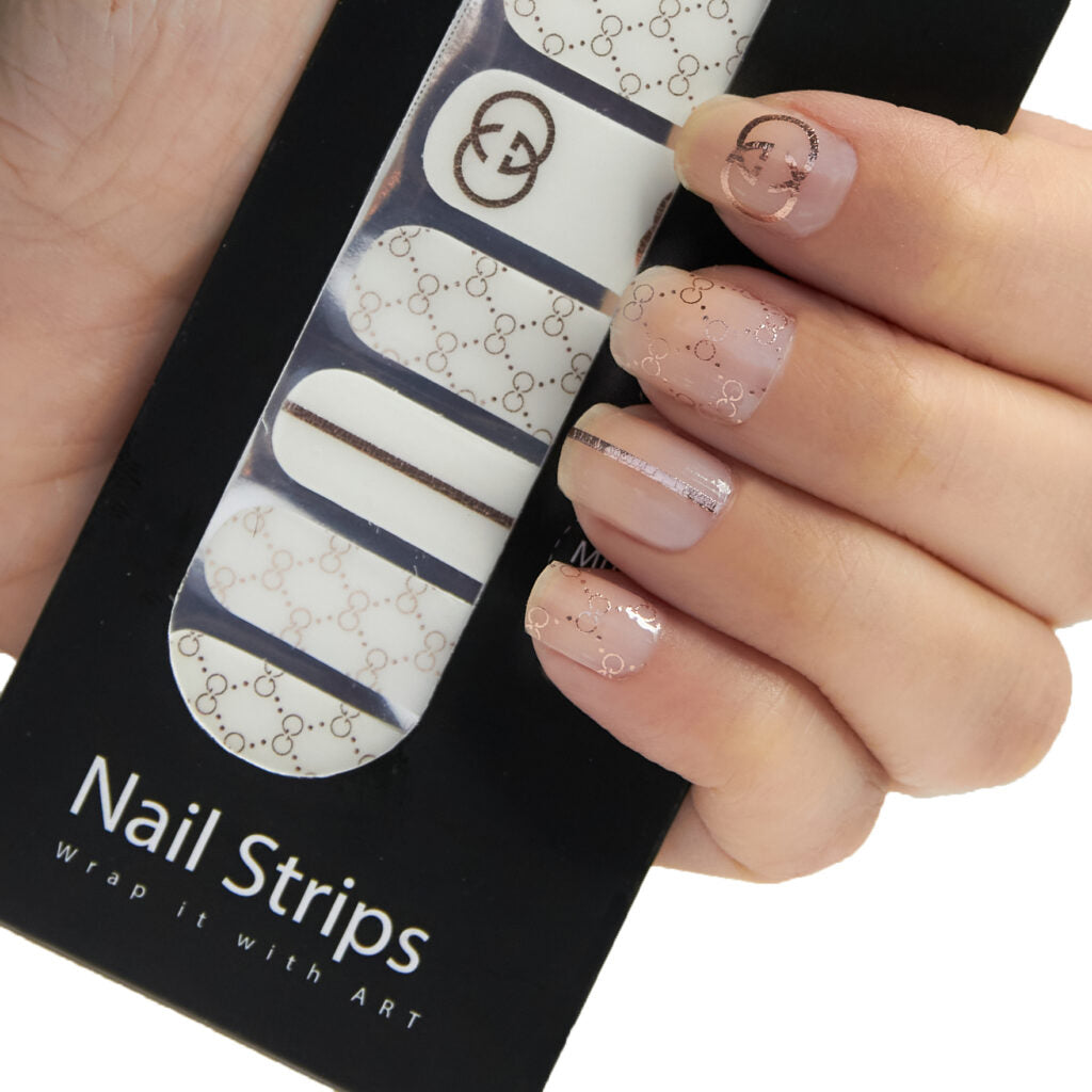 Refect Beauty Yolo nail strips featuring a sheer nude base with metallic gold designer-inspired logo patterns