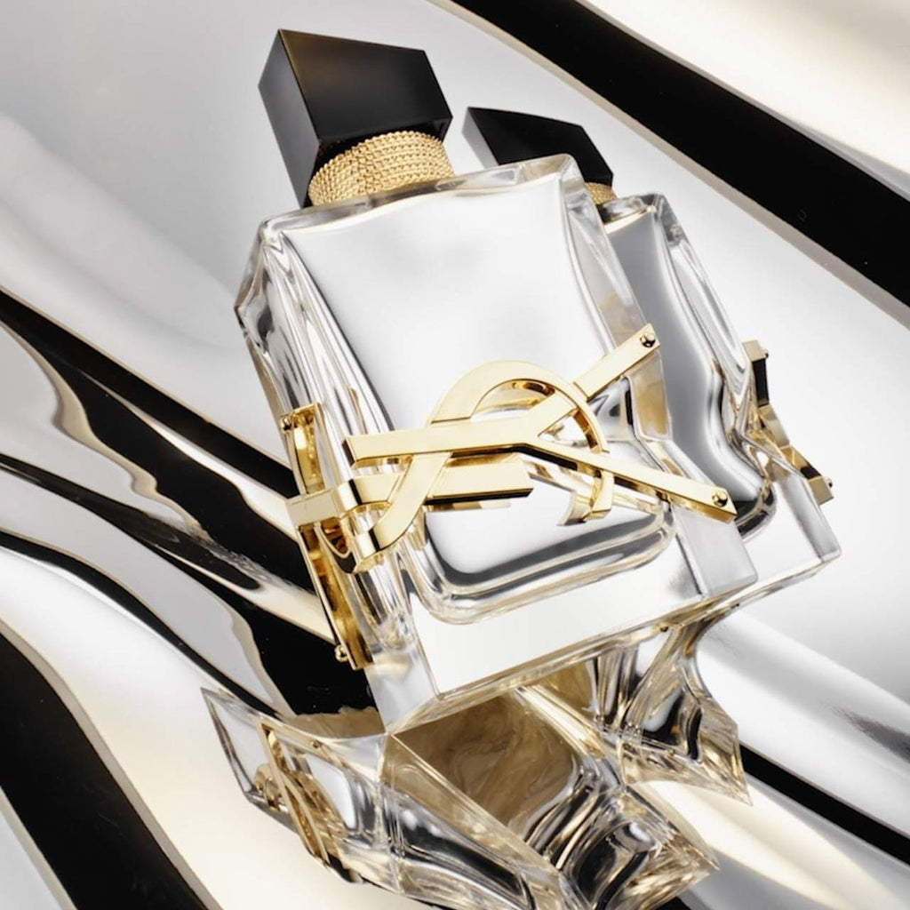 Refect Beauty Yves Saint Laurent Libre L'Absolu Platine perfume bottle with gold YSL logo on a metallic silver surface
