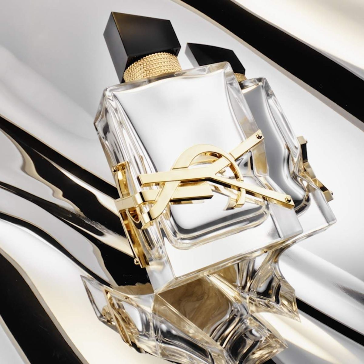 Refect Beauty Yves Saint Laurent Libre L'Absolu Platine perfume bottle with gold YSL logo on a metallic silver surface